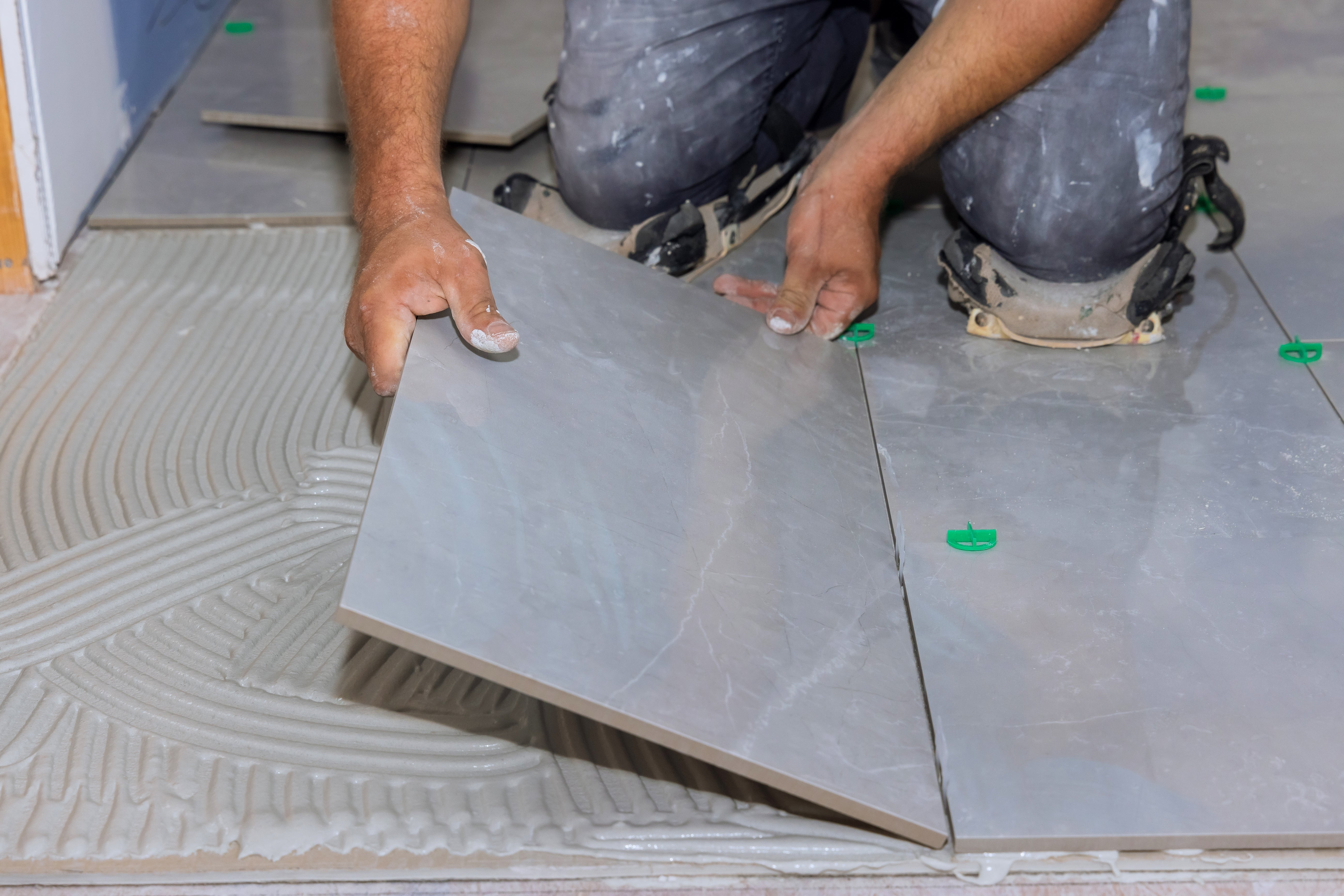 Installateur certifié CCQ posant une céramique 12'' x 24'' sur mortier avec croisillons de nivellement, Surface Expert Drummondville